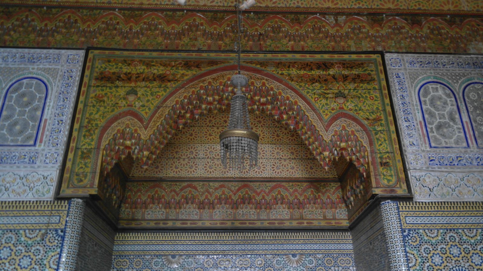 قوس ديال الخشب المزوق، ثريا وحيوط ديال الزليج ف دار مغربية تقليدية